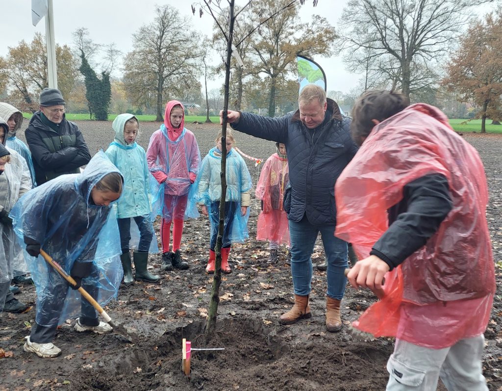 Leerlingen planten een boom met wethouder Nijenbanning tijdens Boomfeestdag